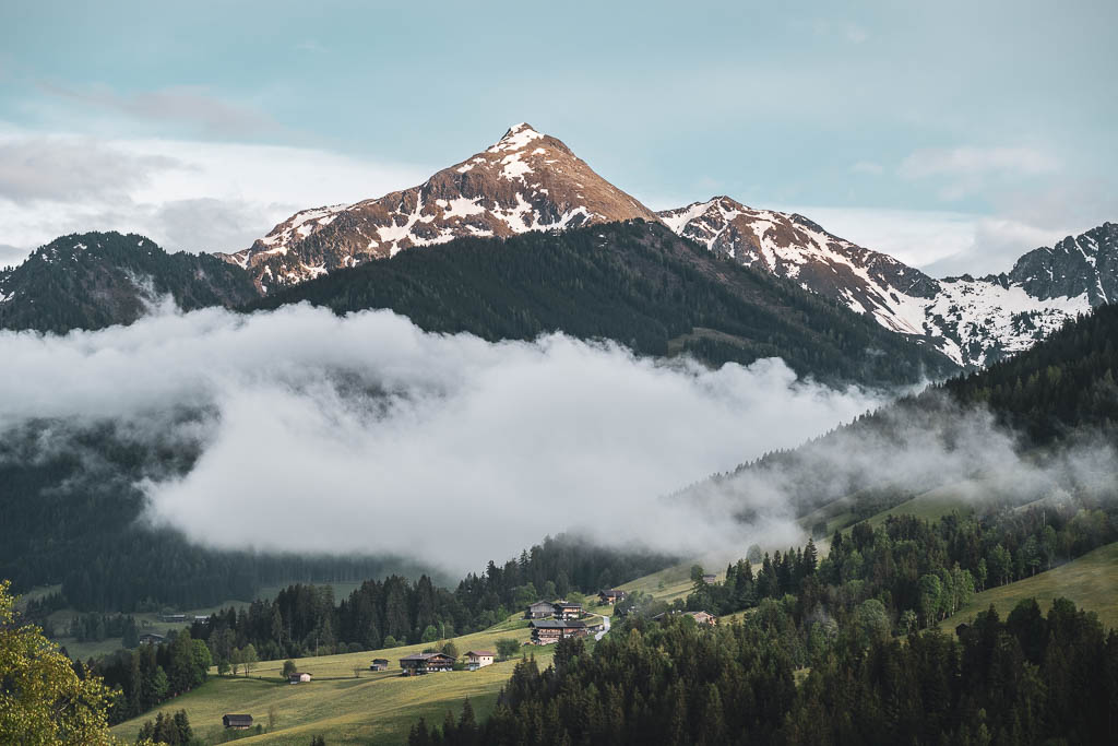Alpbach mit Wolken im Tal und farbigen Berggipfeln bei blauem Himmel