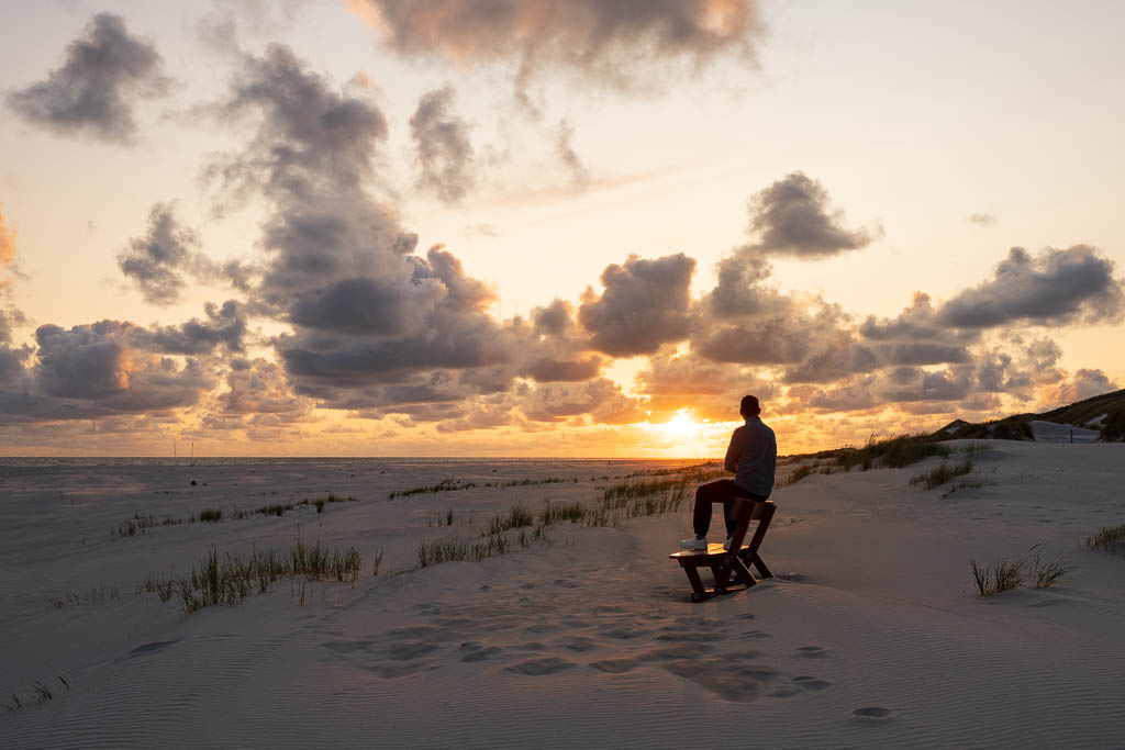 Sonnenuntergang am Kniepsand in Amrum mit einer Person auf einer Holzbank
