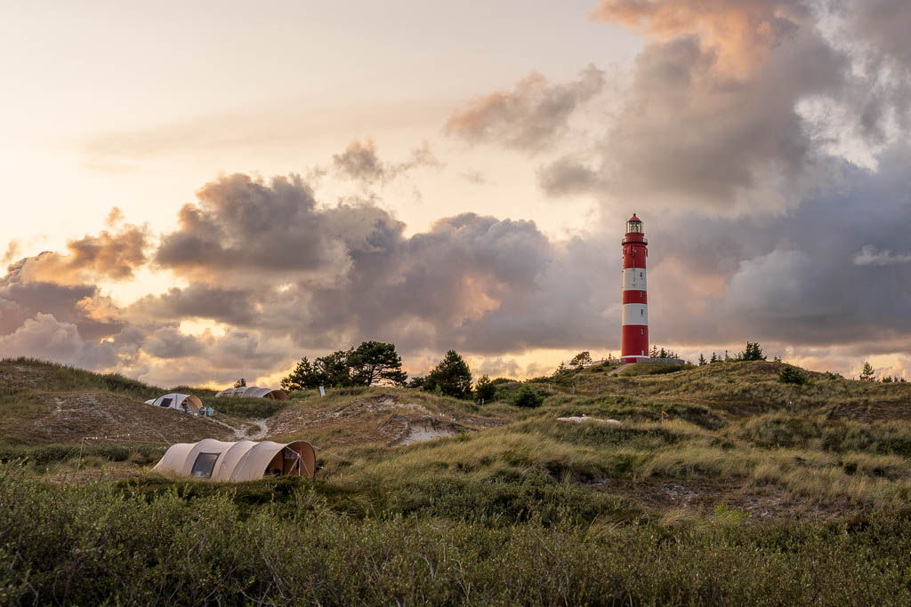 Leuchtturm Amrum zum Sonnenuntergang mit Zelten vom Campingplatz in den Dünen