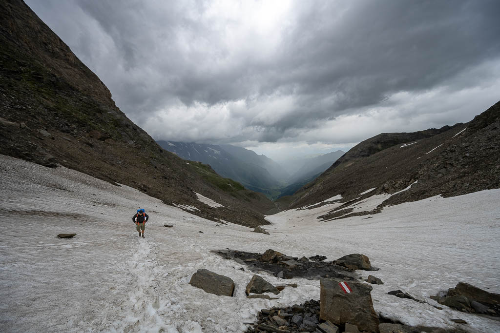 Wanderer vor dunklen Wolken auf dem Weg zur Pfandlscharte