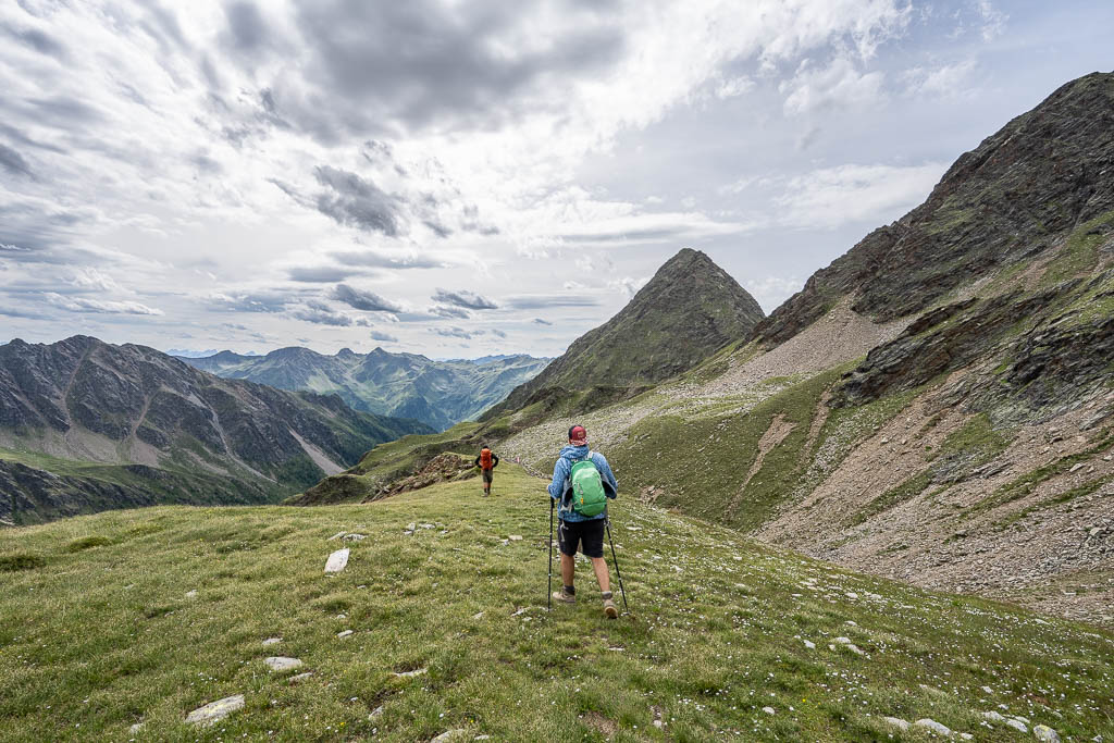 Der Wanderweg führt aus dem felsigen Hochgebirge zurück in die grüne Vegetation.