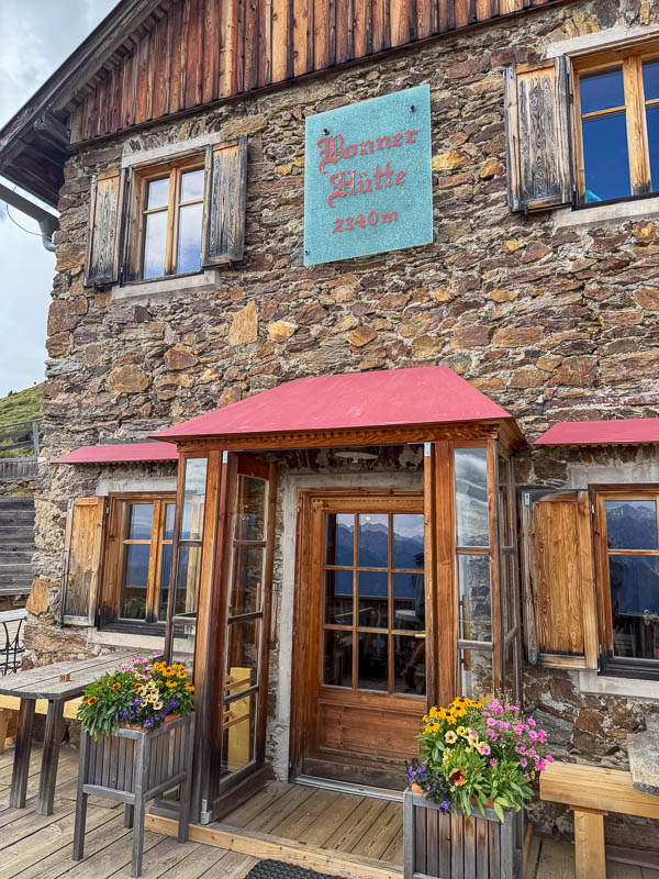 Eingang der Bonnerhütte mit rustikaler Fassade und Blumen vor dem Haus