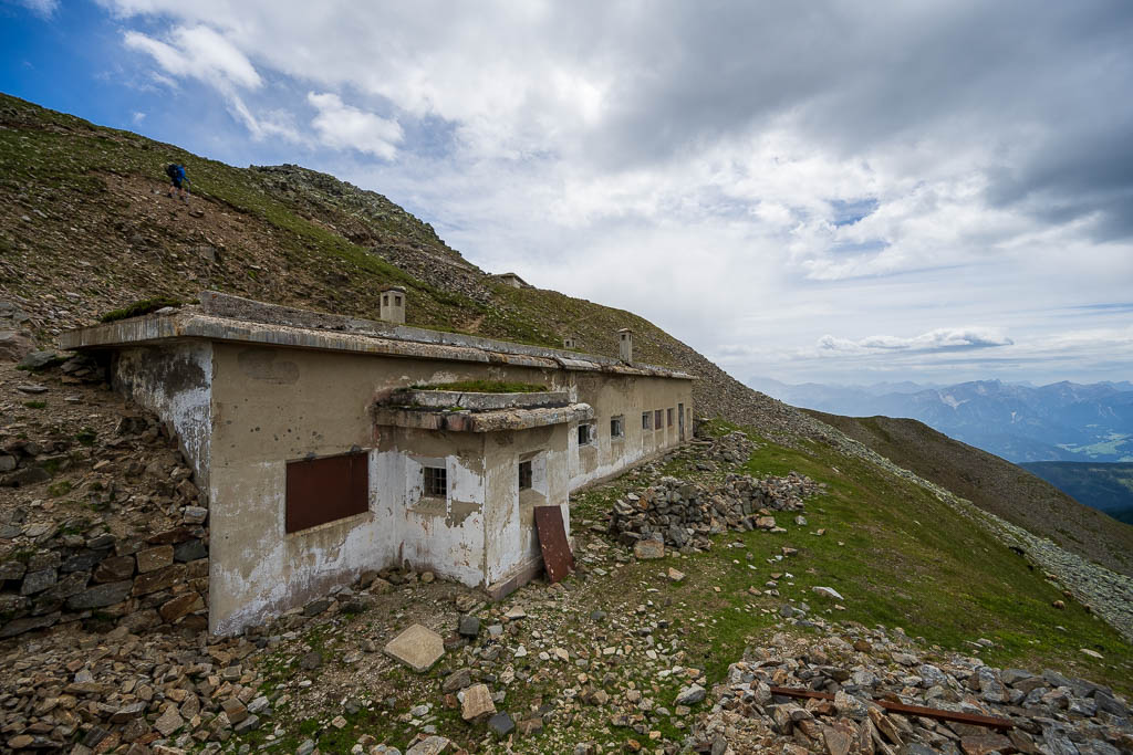 Verfallener Bunker mit breiter Betonfront am steinigen Berghang