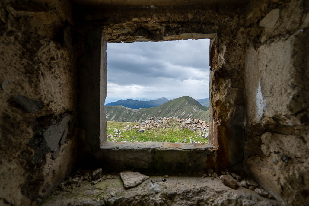 Blick aus einer Öffnung im Inneren eines verlassenen Bunkers auf die Berglandschaft