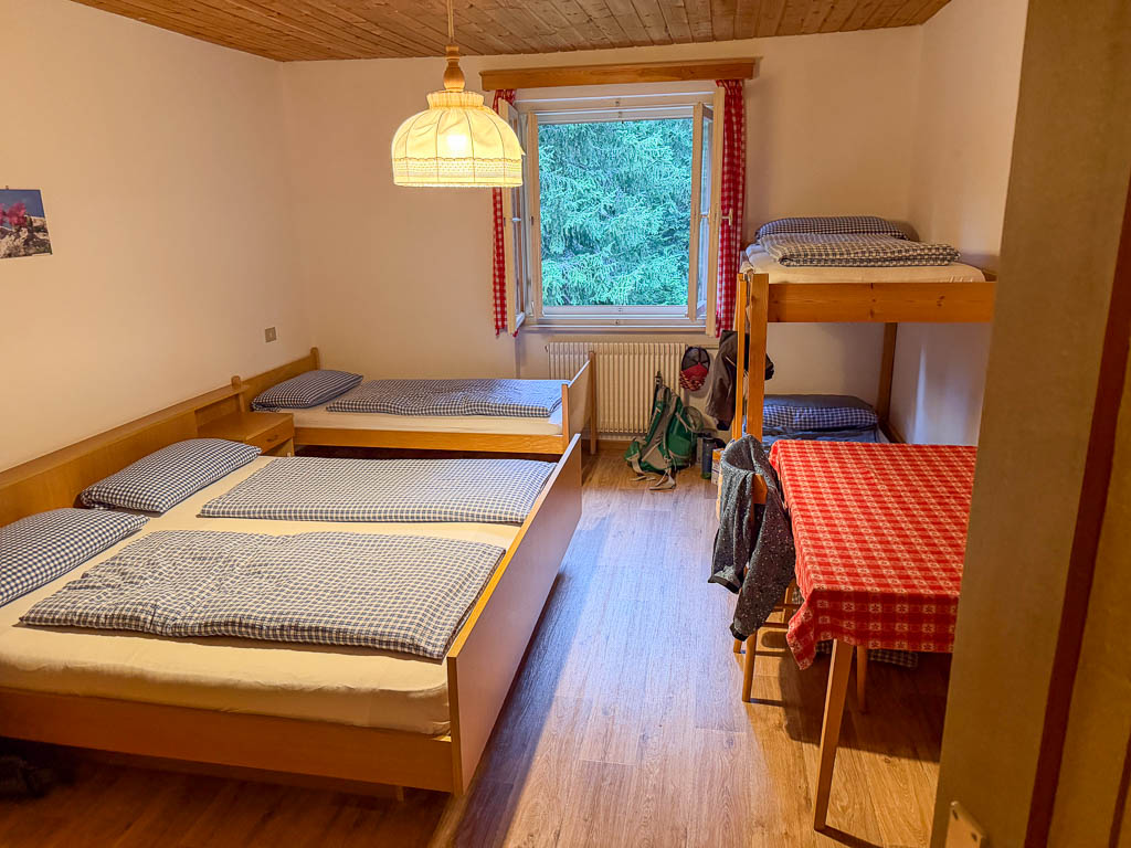 Einfaches Mehrbettzimmer in der Dreischusterhütte mit mehreren Betten und Holzmöbeln