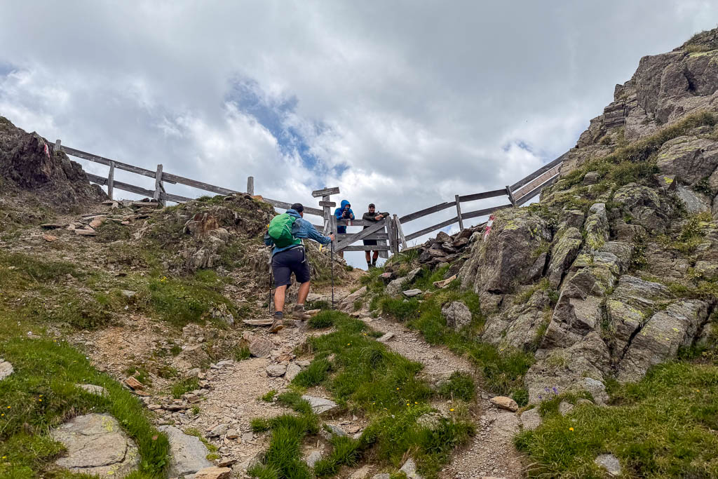 Wanderer steigen über einen steinigen Bergpfad zum Pfanntörl auf
