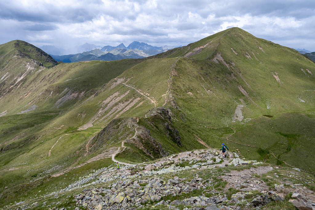Schmaler Wanderweg über einen grünen Bergrücken mit weitem Blick auf die umliegenden Gipfel