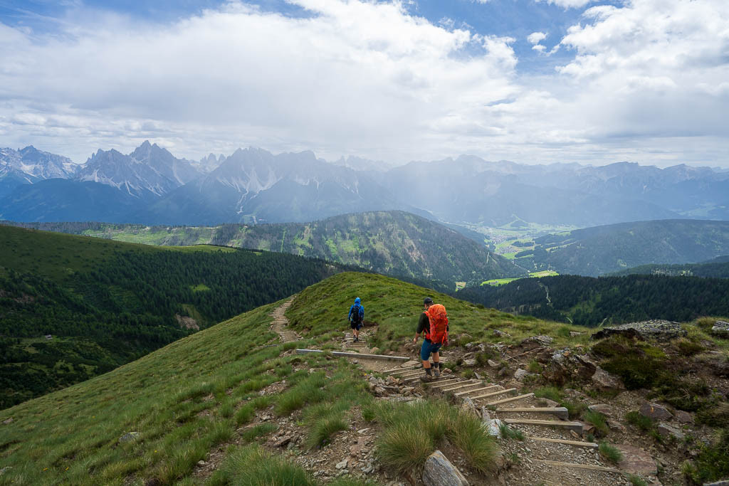 Wanderer auf einem Bergpfad mit weitem Blick auf die Dolomiten
