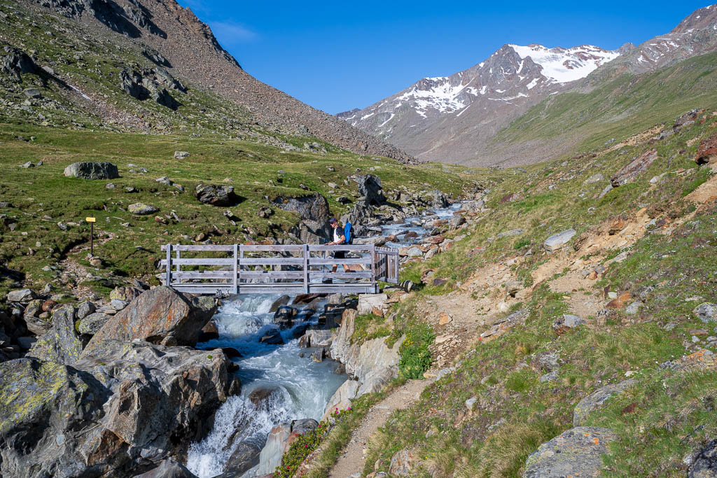 Wanderer auf einer Brücke über dem Niederjoch an der Martin-Busch-Hütte