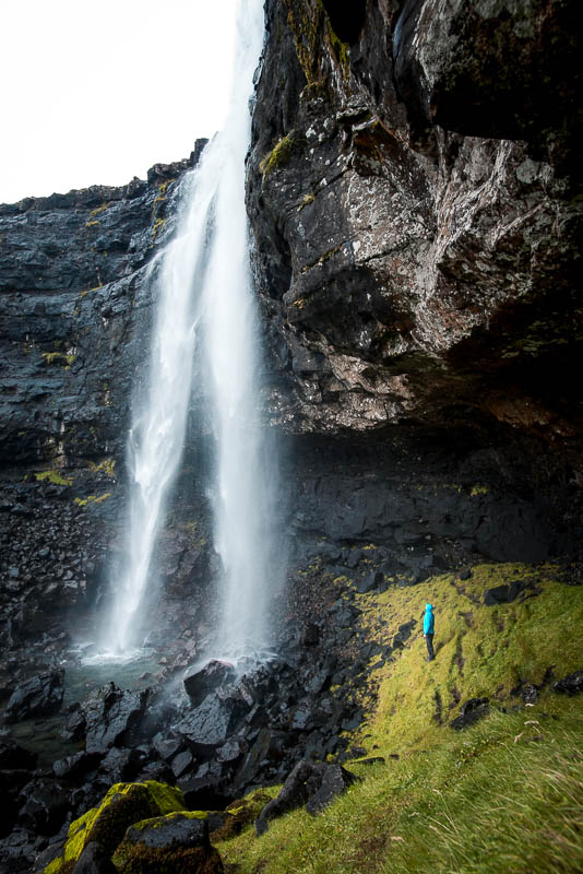 Ein Mensch auf der oberen Ebene vom Fossa Wasserfall auf den Färöer Inseln