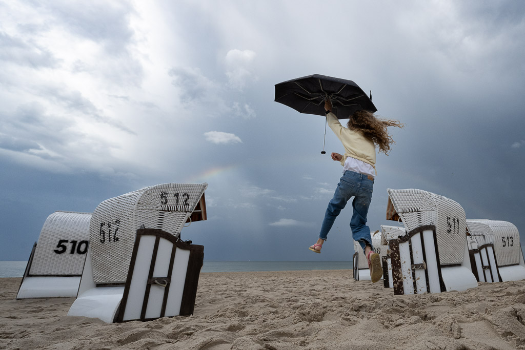 Flug eines kleinen Mädchens mit einem Regenschirm am Strand