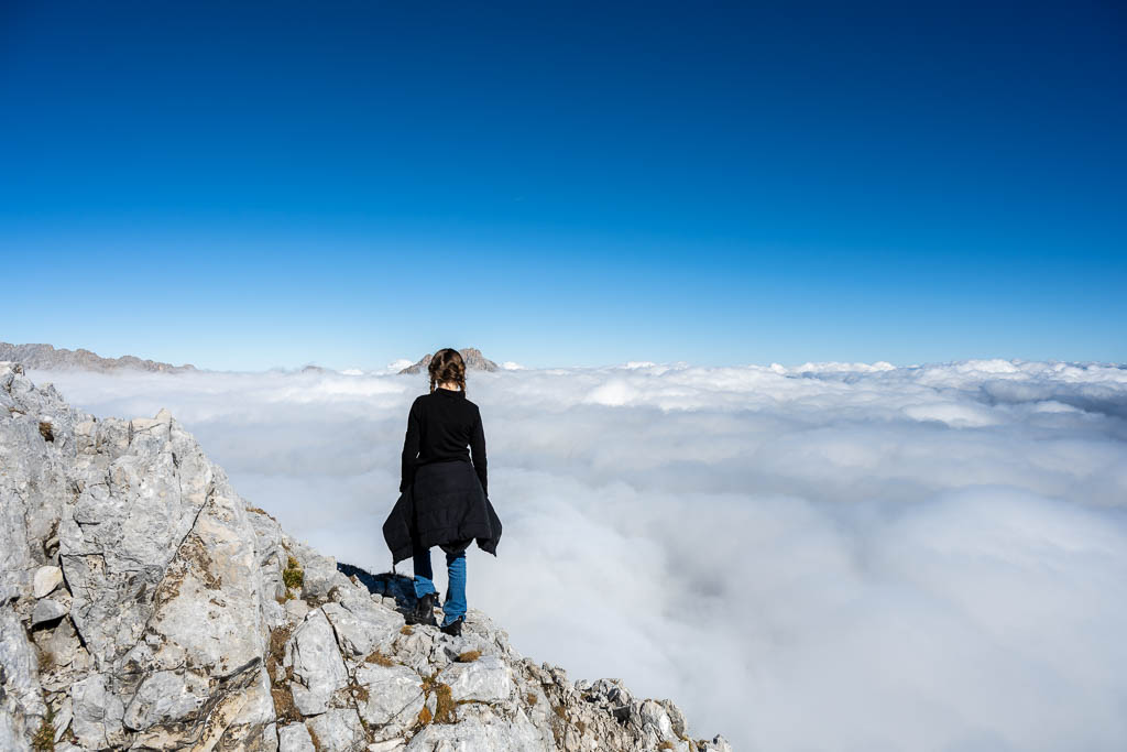 Ein Kind steht auf einem Felsen über den Wolken