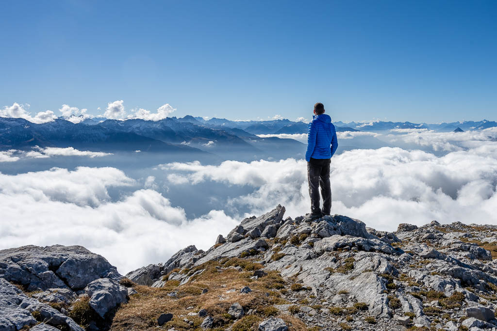 Ein Wanderer steht auf der Hohen Munde und schaut über die Wolken